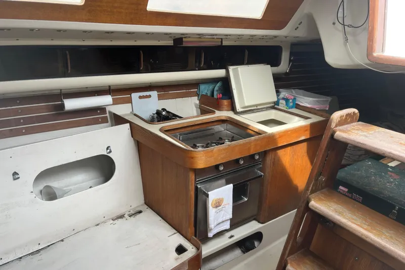 Slide: The Image of Interior of 1986 Alsberg Brothers Express 37 sailboat, featuring a compact wooden galley kitchen. - 24
