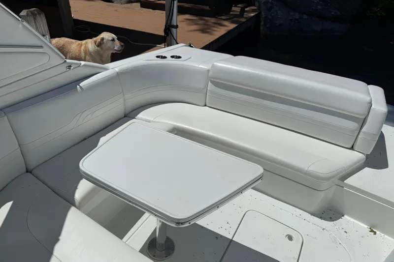 Slide: The Image of 2007 Formula 330 Sun Sport boat interior with white seating and table, dog in background. - 5