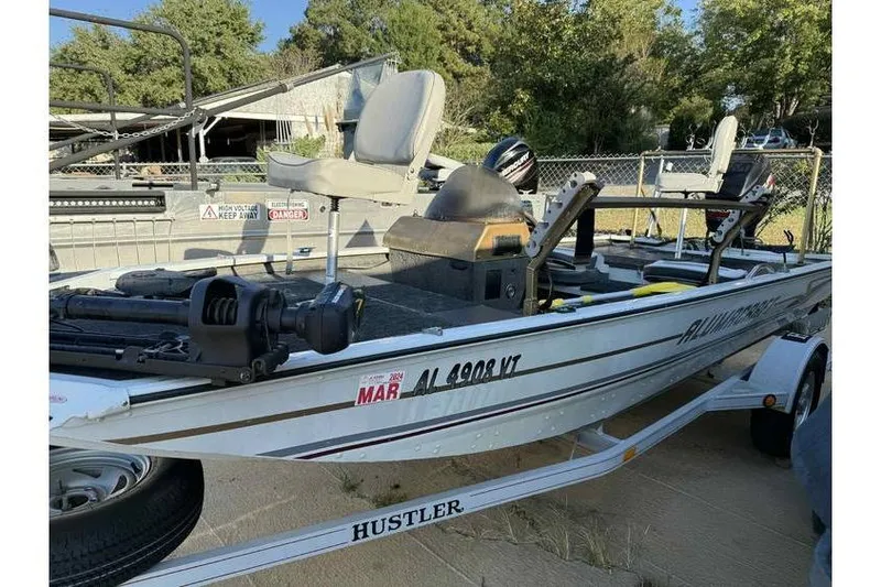Slide: The Image of 1997 Alumacraft Super Bandit boat on trailer, featuring seating and motor, parked outdoors. - 3