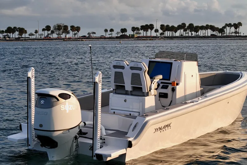 Slide: The Image of 2023 Dynamic D-250DF boat with Suzuki engine on calm water, palm trees in background. - 11