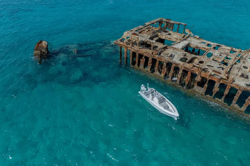 Slide: The Image of Aerial view of Dynamic D-250DF boat near a rusted shipwreck in clear blue waters. - 14