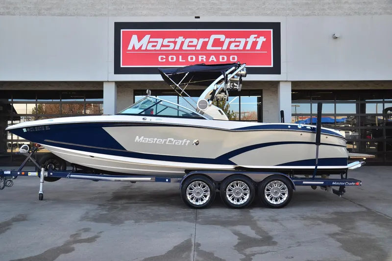 The Image of 2019 MasterCraft X26 boat on trailer at dealership, MasterCraft Colorado sign in background. - 1