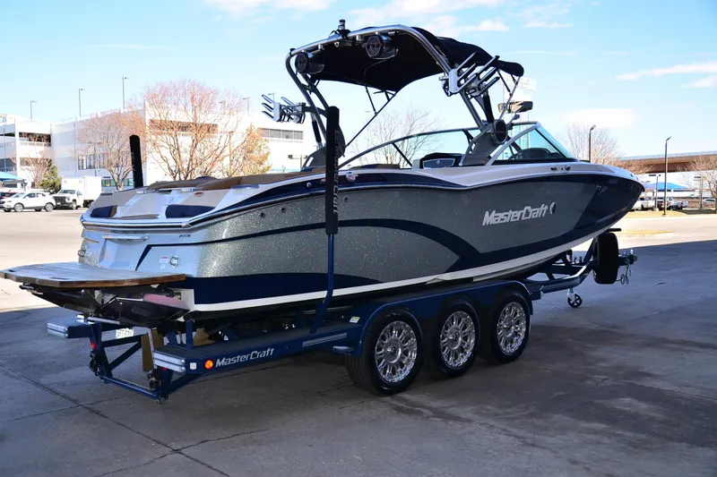 Slide: The Image of 2019 MasterCraft X26 boat on trailer, parked outdoors, showcasing sleek design and modern features. - 3