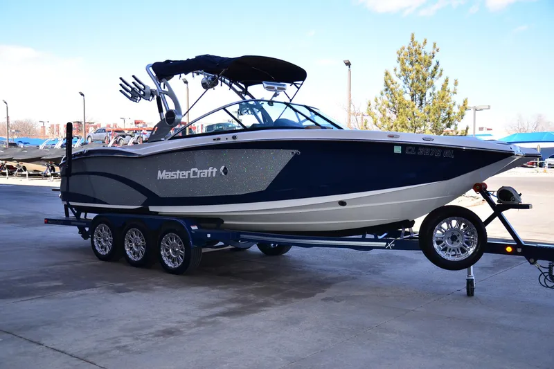 Slide: The Image of 2019 MasterCraft X26 boat on trailer, parked outdoors, showcasing sleek design and modern features. - 5
