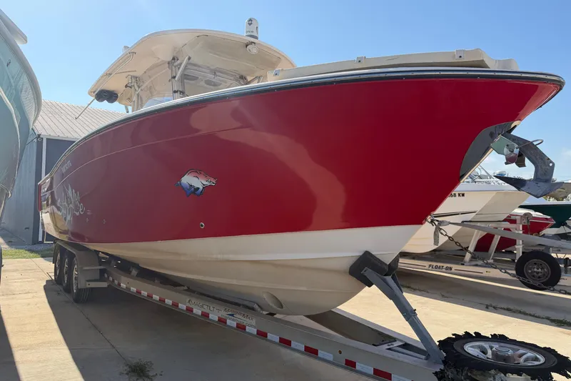 Slide: The Image of 2010 Grady-White Canyon 336 boat with red hull on trailer, parked outdoors. - 24
