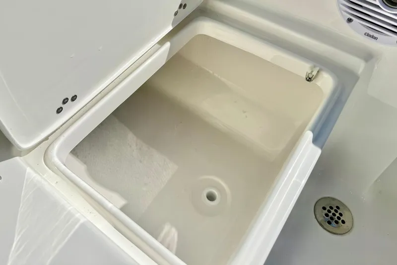 Slide: The Image of Open storage compartment on 2026 Key West 189 FS boat, featuring a drain and speaker. - 27