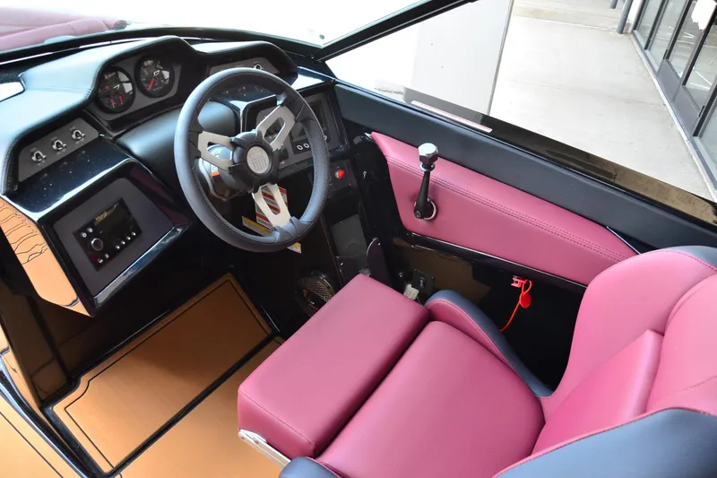 Slide: The Image of 2023 MasterCraft NXT23 boat interior with steering wheel and maroon seating. - 10