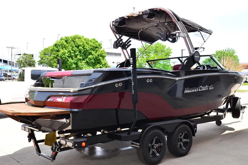 Slide: The Image of 2023 MasterCraft NXT23 boat on trailer, featuring sleek black and red design. - 4