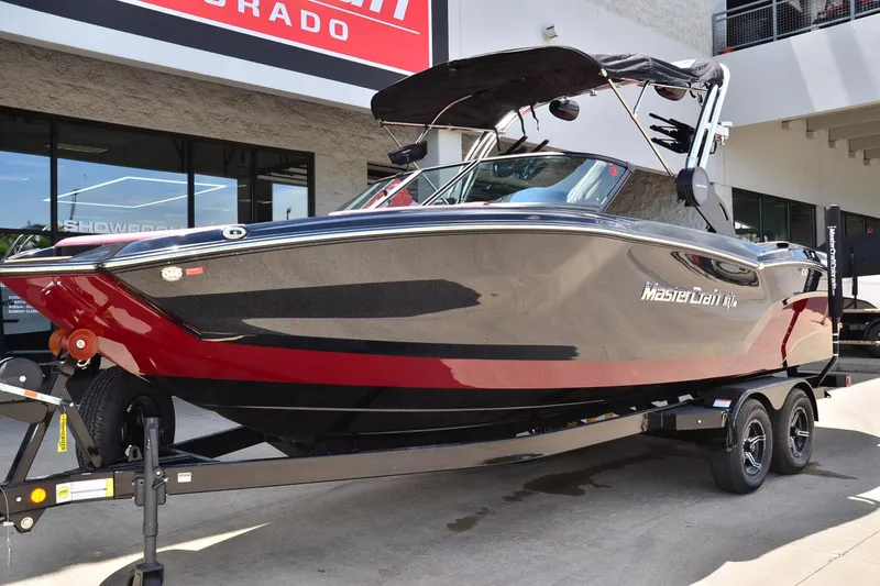 Slide: The Image of 2023 MasterCraft NXT23 boat in showroom, sleek black and red design on trailer. - 7