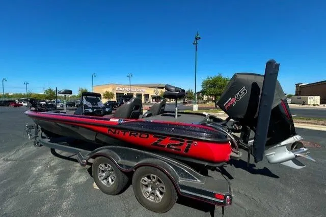 The Image of 2019 Nitro Z21 Elite boat on trailer in parking lot, clear blue sky. - 0