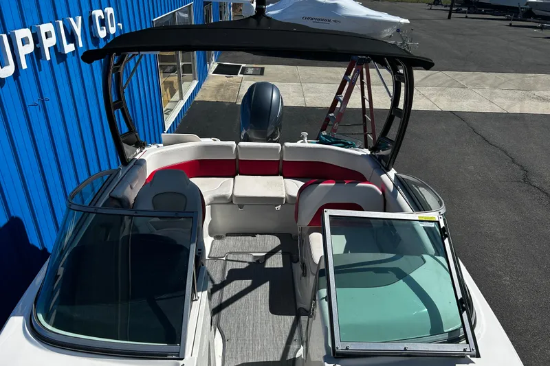 Slide: The Image of 2016 Chaparral 210 Suncoast boat with open seating, docked near blue building. - 14