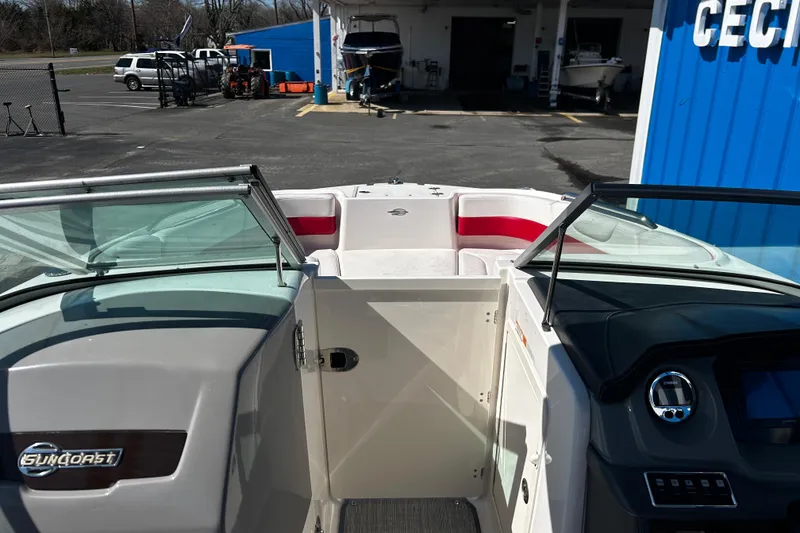 Slide: The Image of 2016 Chaparral 210 Suncoast boat interior with red and white seating, parked outdoors. - 27