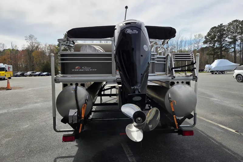 Slide: The Image of 2023 Sun Tracker Fishin' Barge 22 DLX pontoon boat, rear view with motor, parked outdoors. - 3