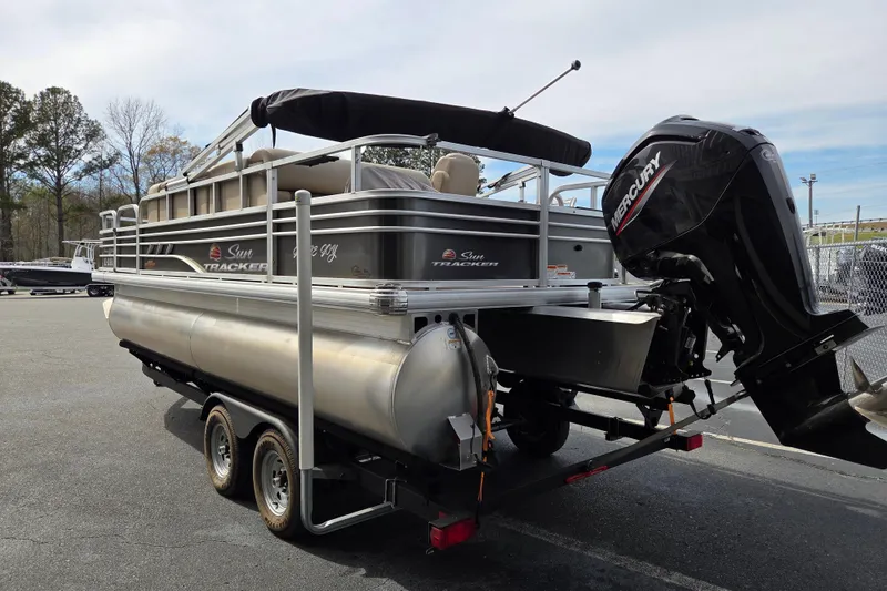 Slide: The Image of 2023 Sun Tracker Fishin' Barge 22 DLX pontoon boat on trailer with Mercury outboard motor. - 4