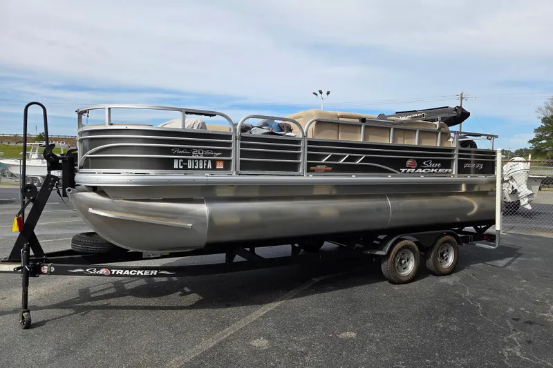 Slide: The Image of 2023 Sun Tracker Fishin' Barge 22 DLX pontoon boat on trailer, parked outdoors. - 6