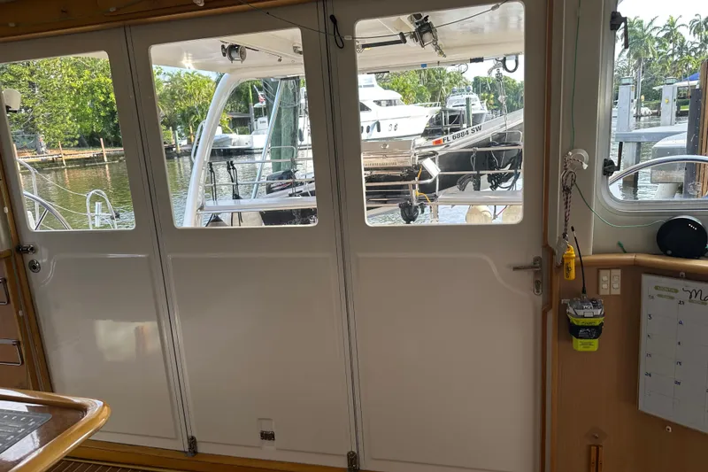 Slide: The Image of Interior view of a 2005 Seawind 1160 catamaran, showcasing the cabin door and marina outside. - 13