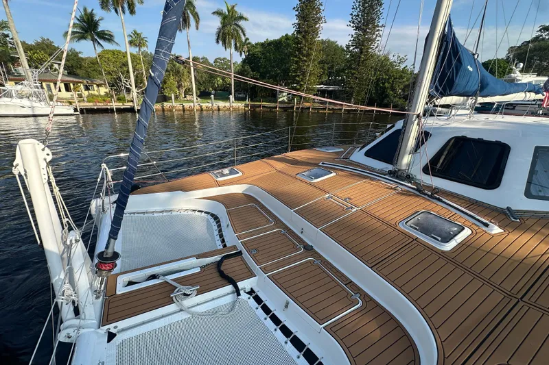 The Image of 2005 Seawind 1160 catamaran with teak deck, docked near palm trees and waterfront homes. - 4