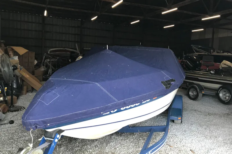 Slide: The Image of 1992 Seaswirl 190 Bowrider I/O boat covered in blue tarp, stored indoors. - 29