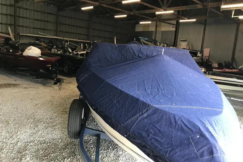 Slide: The Image of 1992 Seaswirl 190 Bowrider I/O covered in blue tarp, stored indoors. - 30