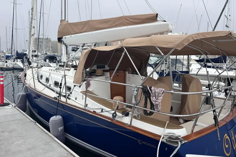 Slide: The Image of Sailboat docked at marina, Tartan 4000 model, 2016, with beige canopy and blue hull. - 6