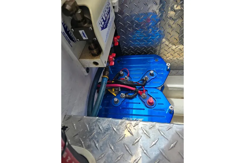 Slide: The Image of 2004 Hustler 388 SLINGSHOT engine compartment with blue battery covers and wiring. - 13