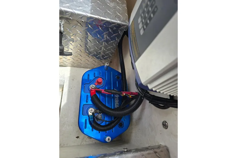 Slide: The Image of 2004 Hustler 388 SLINGSHOT battery compartment with blue cover and wiring. - 15