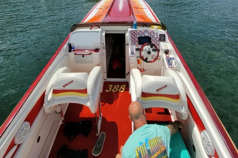 Slide: The Image of 2004 Hustler 388 SLINGSHOT speedboat interior with red and white seating on water. - 5