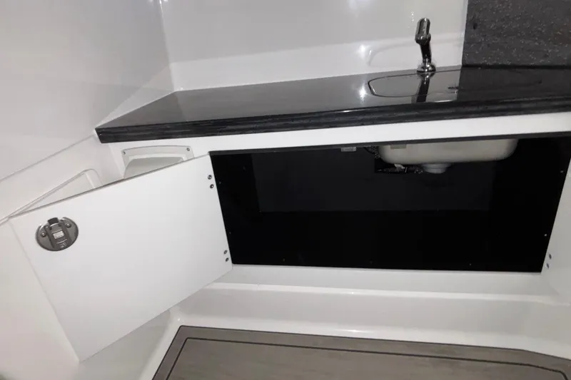 Slide: The Image of Interior of 2026 Monterey Elite 30 OB boat with open cabinet and sink. - 59