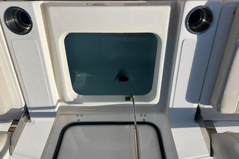 Slide: The Image of 2021 Boston Whaler 250 Dauntless boat storage compartment with open lid and cup holders. - 19