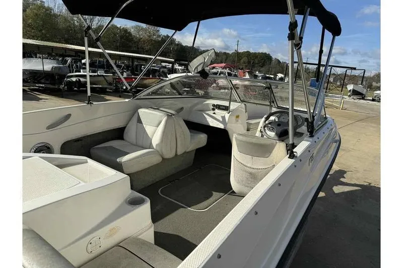 Slide: The Image of 2012 Bayliner 175 Bowrider boat interior with seating and steering wheel, parked outdoors. - 6