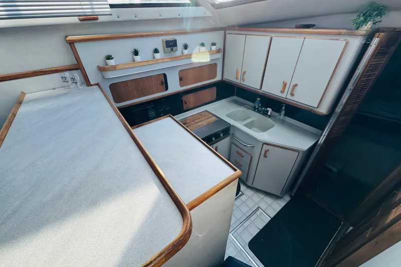 Slide: The Image of 1991 Sea Ray 380 Aft Cabin kitchen with white cabinets and wooden accents. - 25