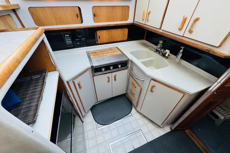 Slide: The Image of 1991 Sea Ray 380 Aft Cabin kitchen with sink, stove, and storage cabinets. - 30
