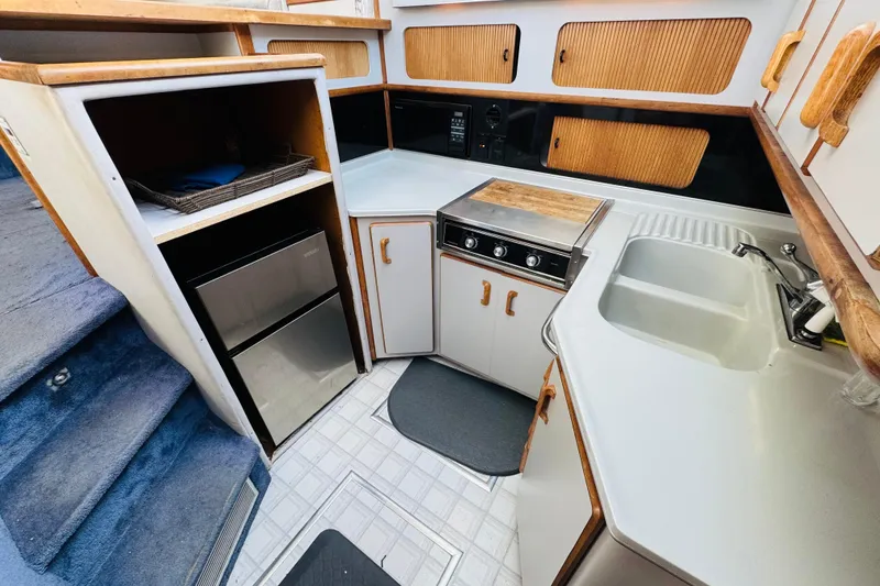 Slide: The Image of 1991 Sea Ray 380 Aft Cabin kitchen with sink, stove, and compact refrigerator. - 31
