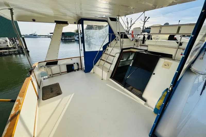Slide: The Image of 1991 Sea Ray 380 Aft Cabin boat deck with marina view, featuring seating and access stairs. - 9