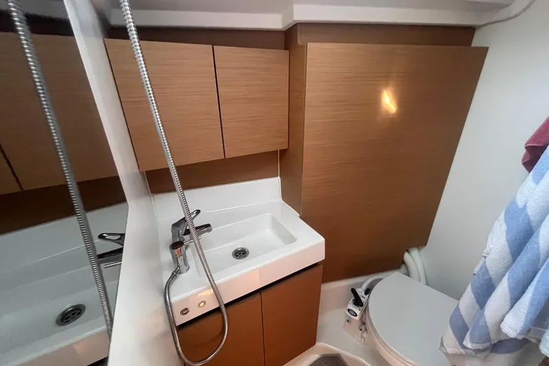 Slide: The Image of Bathroom interior of 2023 Jeanneau Sun Odyssey 380 yacht, featuring modern fixtures and wooden cabinetry. - 10