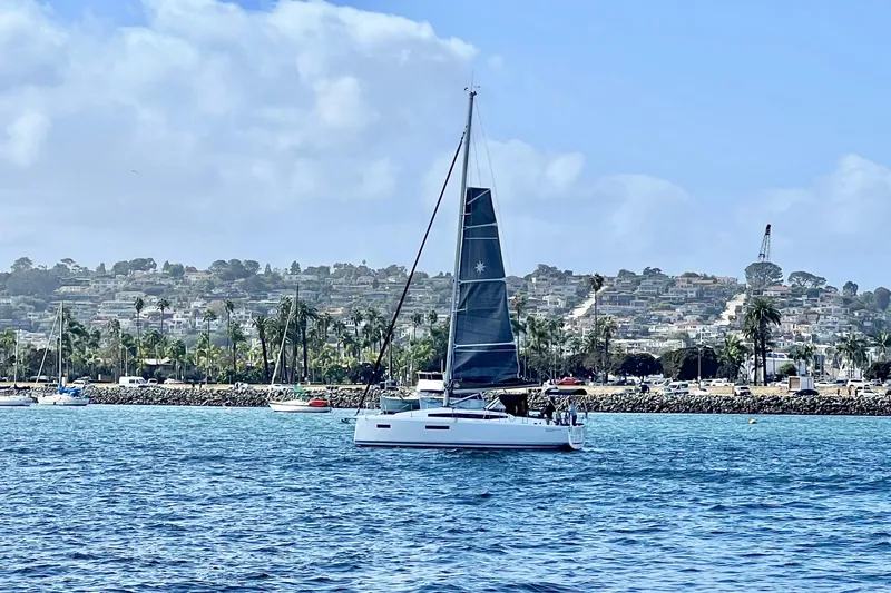 Slide: The Image of 2023 Jeanneau Sun Odyssey 380 sailing near a coastal cityscape under a clear blue sky. - 60