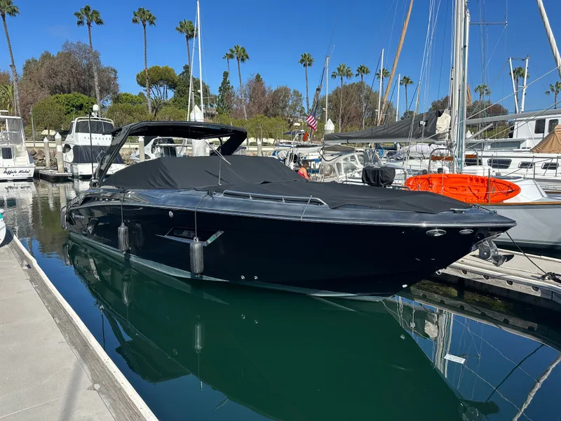 Slide: The Image of A sleek black motorboat docked in a marina, surrounded by other boats and palm trees. - 28