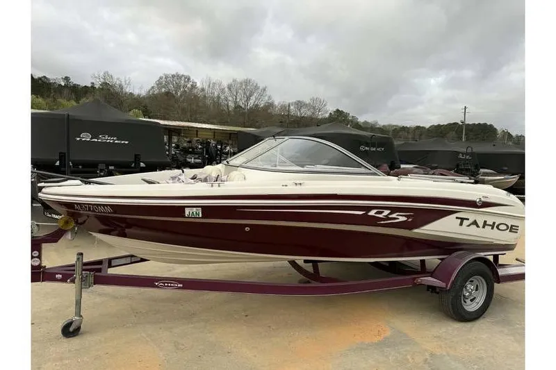 Slide: The Image of 2014 Tahoe Q5i SF boat on trailer, parked outdoors under cloudy sky. - 2