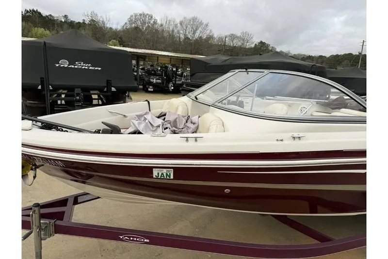 Slide: The Image of 2014 Tahoe Q5i SF boat on trailer, parked outdoors with covered boats in background. - 4