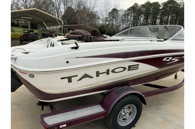 Slide: The Image of 2014 Tahoe Q5i SF boat on trailer, white and maroon, parked outdoors. - 7