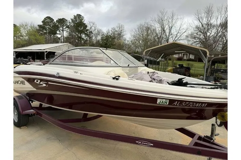 Slide: The Image of 2014 Tahoe Q5i SF boat on trailer, parked outdoors with trees in background. - 9