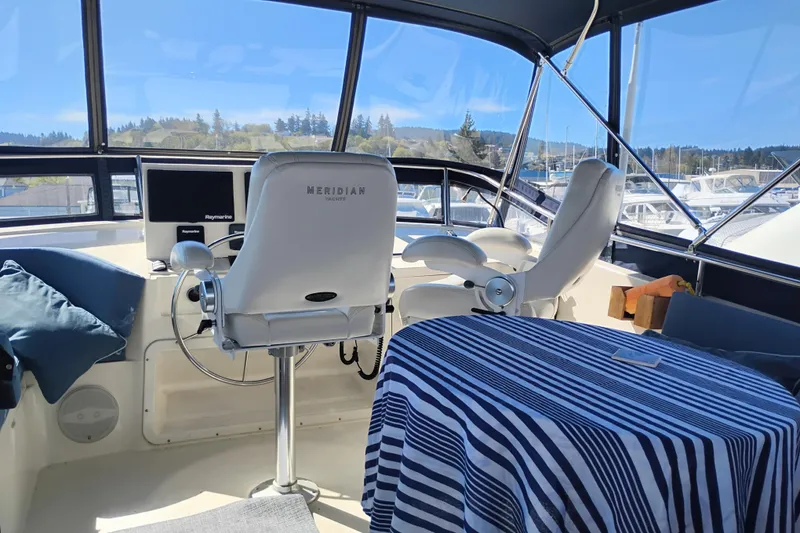 Slide: The Image of 1988 PT 52 AFT Cabin Motor Yacht interior with helm, striped tablecloth, and scenic marina view. - 24