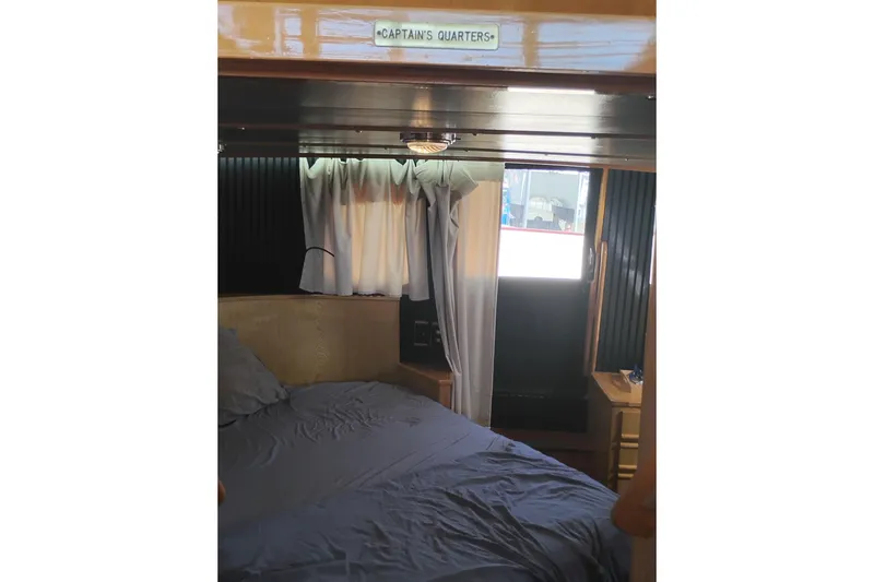 Slide: The Image of Captain's quarters in 1988 PT 52 AFT Cabin Motor Yacht, featuring cozy bedding and window. - 60