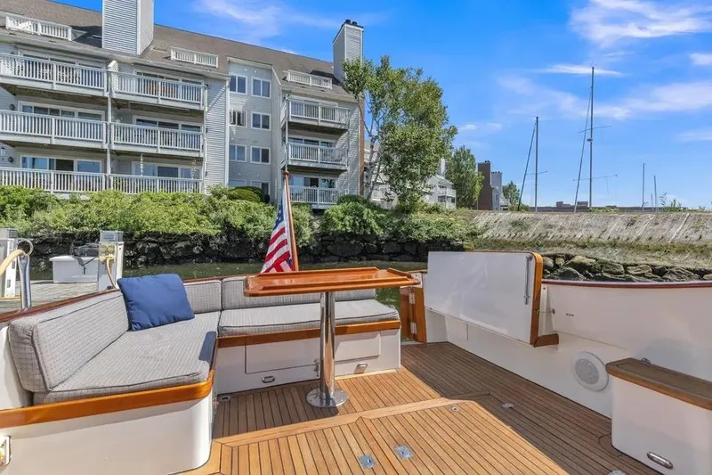 Slide: The Image of 2007 Gorbon Custom Downeast 40 yacht deck with seating, docked near waterfront apartments. - 16