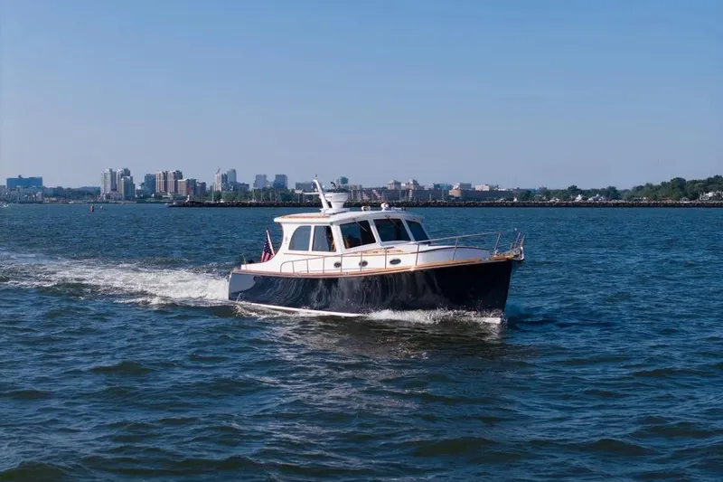Slide: The Image of 2007 Gorbon Custom Downeast 40 yacht cruising on open water with city skyline backdrop. - 6