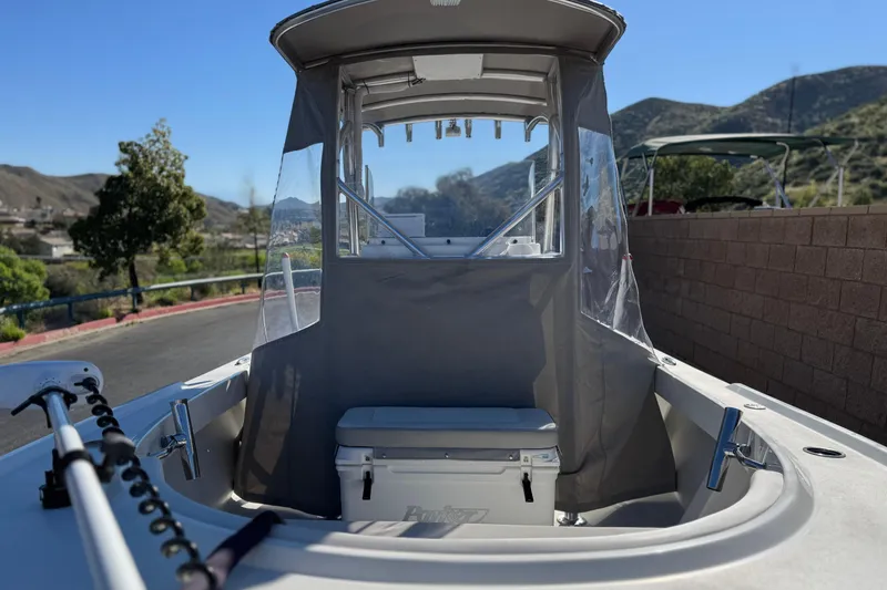 Slide: The Image of 2023 Parker 21SE Center Console boat with protective cover, parked near scenic hills. - 10