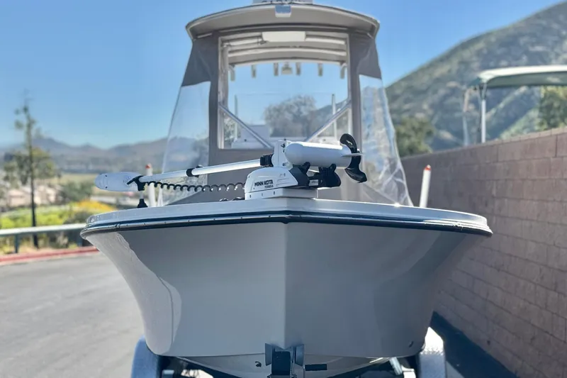 Slide: The Image of 2023 Parker 21SE Center Console boat with Minn Kota trolling motor, parked outdoors. - 2