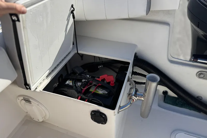 Slide: The Image of Open storage compartment on 2023 Parker 21SE Center Console boat, revealing battery and wiring. - 23