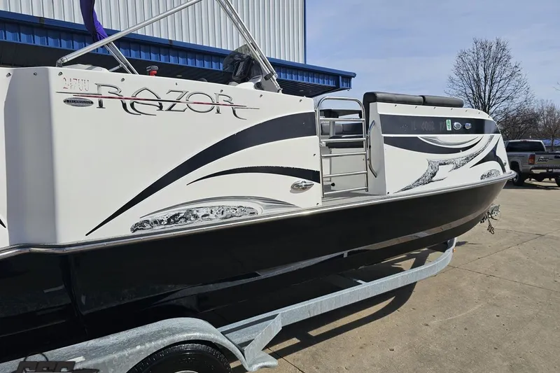 Slide: The Image of 2014 Caravelle 247 UU Razor E-Toon boat on trailer, sleek design, outdoor setting. - 10