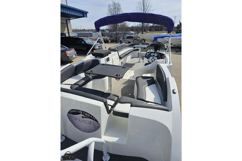 Slide: The Image of 2014 Caravelle 247 UU Razor E-Toon boat with seating and canopy, parked outdoors. - 38